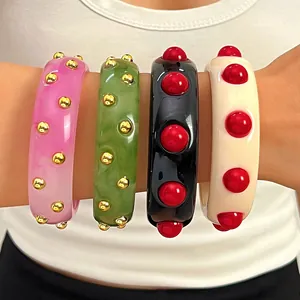 Detail showing four vibrant vintage acrylic bangles with decorative studs on model