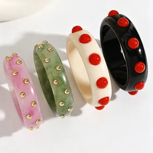 Close-up of retro colorful acrylic wide bangles with decorative studs in multiple colors