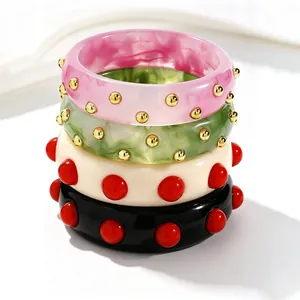 Close-up macro view of four retro colorful dotted wide acrylic bangles in stacked style