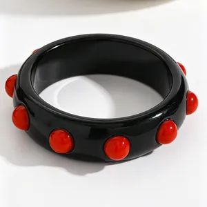 Detailed view of vintage black acrylic wide bangle with red sphere studs decor