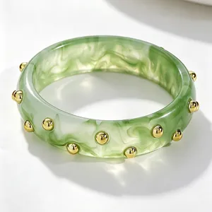 Detailed view of a vintage green marbled acrylic wide bangle with gold studded accents