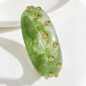 Close-up of green marbled acrylic bangle with gold metallic stud embellishments
