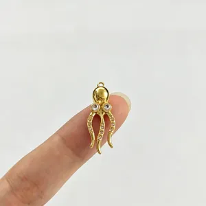 Detailansicht eines winzigen goldenen Krakenanhängers mit glitzernden Strasssteinen am Finger.