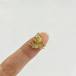 Detaillierte Makroansicht eines goldenen Krakenanhängers mit Zirkonia auf einem Finger