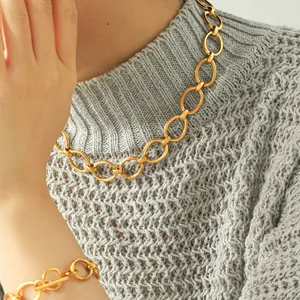 Close-up detail of a gold titanium steel necklace and bracelet set on a grey sweater