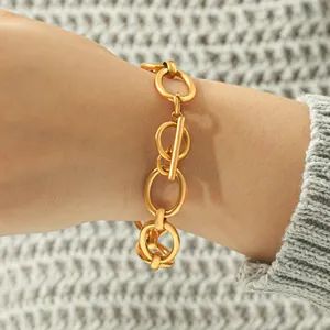 Close-up of a gold stainless steel chain bracelet with a geometric OT toggle clasp