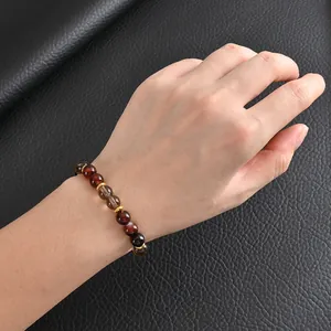 Gros plan détaillé d'un bracelet en perles d'agate marron et café fait à la main sur un poignet.