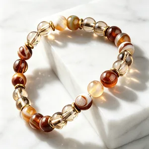 Gros plan de perles d'agate marron et d'entretoises dorées sur du marbre blanc