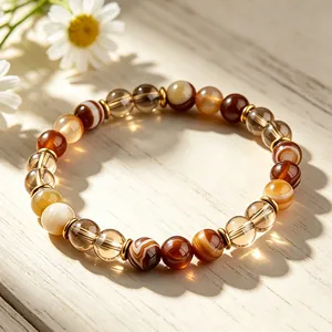 Gros plan d'un bracelet en perles d'agate marron avec intercalaires dorés sur bois.