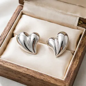 Dettaglio di orecchini a lobo vintage in argento a cuore in una scatola di legno