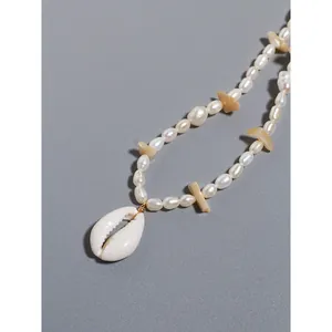 Dettaglio ravvicinato del ciondolo in conchiglia naturale su collana di perle estiva