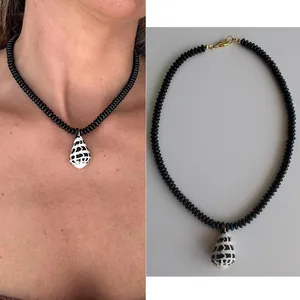 Dettaglio della collana di perle nere con ciondolo a conchiglia per stile spiaggia