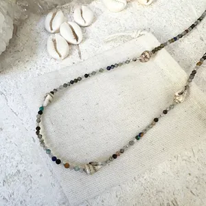 Dettaglio di una collana da spiaggia boho con perle sfaccettate e conchiglie vere.