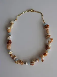 Dettaglio di una collana in stile spiaggia con conchiglie naturali e perline