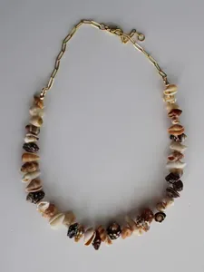 Dettaglio di una collana in stile spiaggia con conchiglie naturali e catena dorata