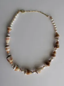 Dettaglio della collana da spiaggia con conchiglie a cono e perle bianche su catena.