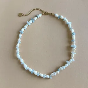 Primo piano di una collana in stile spiaggia con conchiglie bianche e pietre naturali azzurre