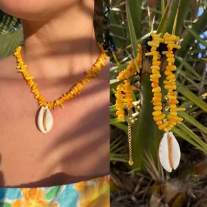 Primo piano di una collana da spiaggia con ciondolo a conchiglia e perline gialle.
