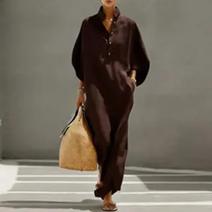 Vestido largo marrón con mangas linterna, botones y bolso de paja.