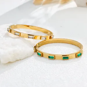 Macro detail of gold-plated stainless steel bangles with green and white baguette stones