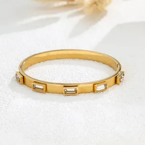 Detail view of a gold-plated stainless steel bangle featuring inlaid rectangular crystals.