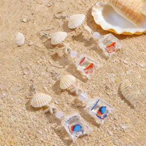 Vue détaillée des boucles d'oreilles thème océan avec coquillages et breloques poisson.
