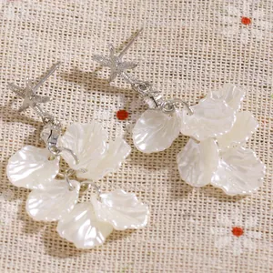 Détail de boucles d'oreilles océan avec étoiles de mer argentées et pétales de coquillages