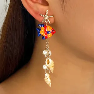 Détail d'une boucle d'oreille vintage style océan avec étoile de mer et coquillage.