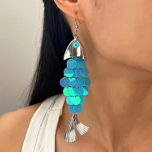 Vue rapprochée d'une boucle d'oreille bohème en forme de poisson avec paillettes bleues et argent