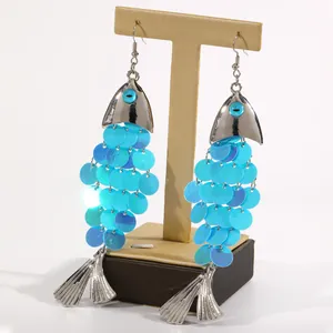 Vue détaillée de grandes boucles d'oreilles poisson en paillettes bleues sur un support