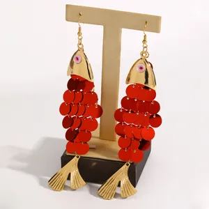 Vue détaillée de boucles d'oreilles poisson à paillettes rouges et nageoires dorées