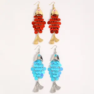 Gros plan de boucles d'oreilles pendantes en forme de poisson à paillettes rouges et bleues