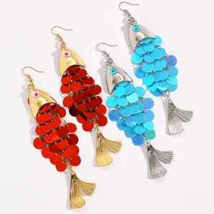 Gros plan de boucles d'oreilles pendantes en forme de poisson à paillettes rouge et bleu