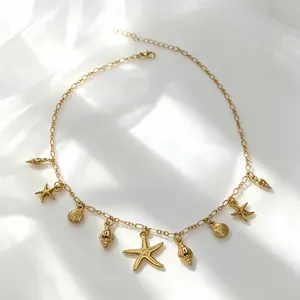 Close-up of gold bohemian necklace with starfish and shell pendants on white fabric