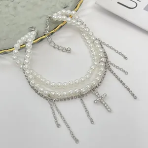 Detail view of multi-layered faux pearl anklet with rhinestone cross pendant and chains