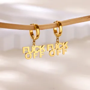 Vue détaillée de créoles dorées avec des pendentifs audacieux portant le message 'FUCK OFF'.