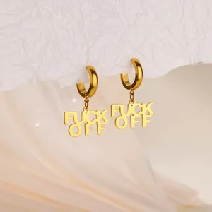 Gros plan détaillé de boucles d'oreilles créoles dorées avec pendentifs FUCK OFF