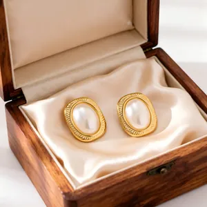 Detailed macro shot of elegant French vintage pearl stud earrings in a wooden jewelry box.