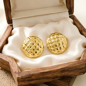 Detail view of gold stainless steel round earrings with quilted texture in a box