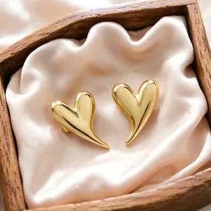 Detailed close-up of golden heart-shaped stud earrings in a rustic wooden gift box