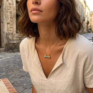 Detail of a 18K gold plated capsule necklace with turquoise beads worn by a model
