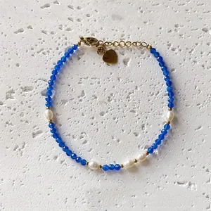 Handmade blue faceted stone and freshwater pearl choker necklace detail on stone surface