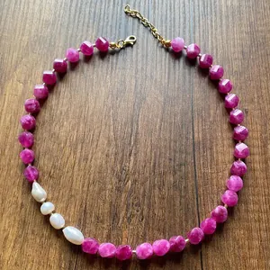 Close-up of a handmade necklace featuring pink faceted natural stones and freshwater pearls