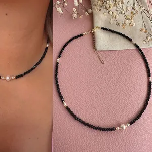 Close-up detail of handmade black natural stone beaded necklace with freshwater pearl accents