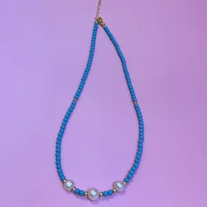Detailed view of turquoise beaded necklace featuring three central freshwater pearls