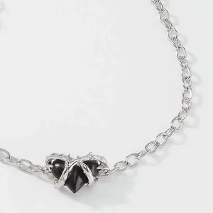 Nahaufnahme eines gotischen schwarzen Herzanhängers mit silbernen Dorndetails Kette