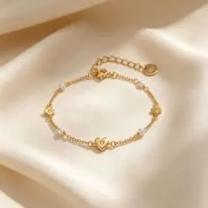 Détail en gros plan d'un élégant bracelet en or avec cœur et perles sur satin de luxe