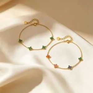 Gros plan de bracelets en argent plaqué or avec des breloques trèfle colorées sur soie