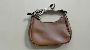 Close-up of a vintage brown crescent shoulder bag with adjustable webbing strap