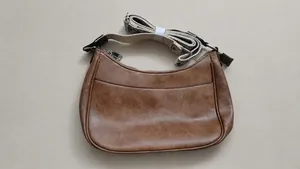 Detailed view of a vintage brown crescent shoulder bag with adjustable woven strap